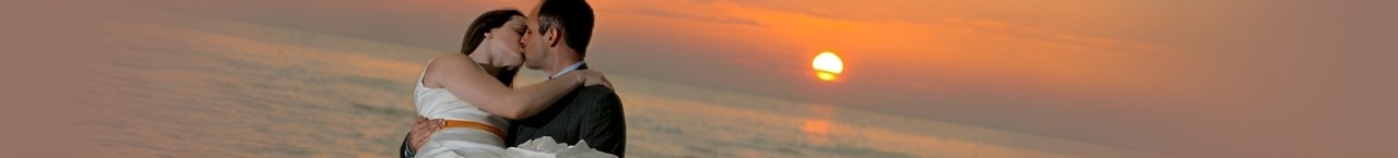 Couple sharing a kiss at sunset on the beach, capturing a romantic moment. Highlights love and intimacy against a vibrant ocean backdrop.