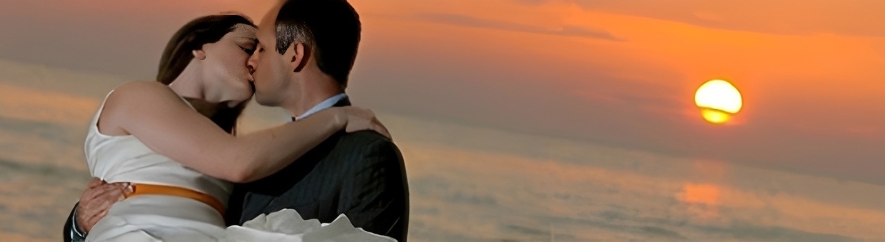 Couple sharing a kiss at sunset on the beach, capturing a romantic moment. Highlights love and intimacy against a vibrant ocean backdrop.